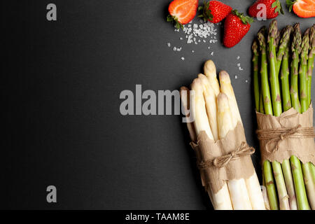 Frischer grüner und weißer Spargel mit Erdbeeren auf der Tafel Stockfoto