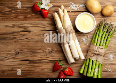 Frischer grüner und weißer Spargel mit Erdbeeren auf rustikalen Holztisch Hintergrund Stockfoto