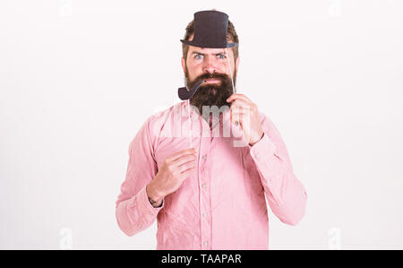 Guy raucht Tabakpfeife. Hipster mit Bart und Schnurrbart auf ernstes Gesicht mit Photo Booth Requisiten posieren. Aristokratie Konzept. Mann hält Papier Partei Requisiten Tabakpfeife und Hut, weißen Hintergrund. Stockfoto