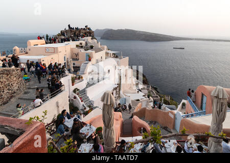 Santorini, Griechenland - 7. Mai 2019: Eine große Menge von Touristen an der berühmten Aussichtspunkt in Oia versammeln, um den Sonnenuntergang über dem berühmten Dorf in Santori zu prüfen. Stockfoto