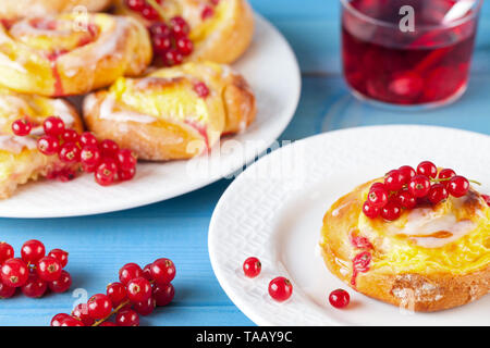 Blätterteig mit Pudding und rote Johannisbeeren auf einem blauen Holztisch. Fruit Cake. Stockfoto