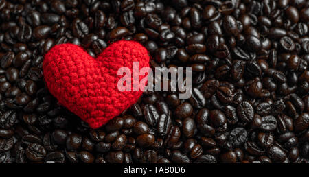 Rotes Herz auf eine Menge von gerösteten Kaffeebohnen Hintergrund. Starken schwarzen Kaffee Espresso, Körner, Hintergrund, Textur Stockfoto