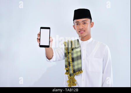 Porträt eines lächelnden jungen muslimischen Mann in weißer Bildschirm Mobiltelefon über weißem Hintergrund zeigen Stockfoto