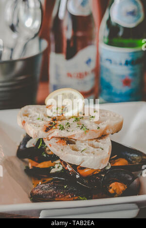 Saute Muscheln in Weißwein und Knoblauch Sauce serviert mit Knoblauch Brot auf der Oberseite Stockfoto