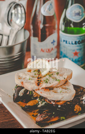 Saute Muscheln in Weißwein und Knoblauch Sauce serviert mit Knoblauch Brot auf der Oberseite Stockfoto