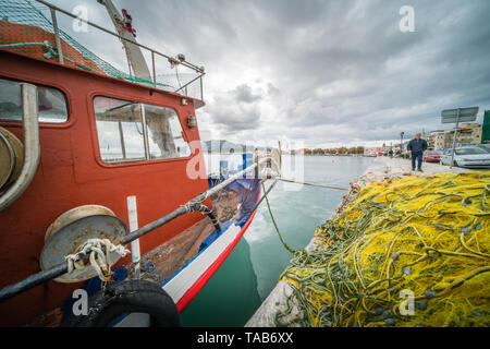 Zakynthos, Griechenland - April 2019: Große Haufen von Netzen und Fischer Boot am Ufer vertäut im Hafen von Zakynthos, Ionische Inseln Stockfoto