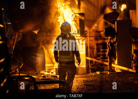 Feuerwehrleute rund um ein Feuer, verursacht durch eine Falla Valenciana Controlling die Flammen des Feuers. Stockfoto