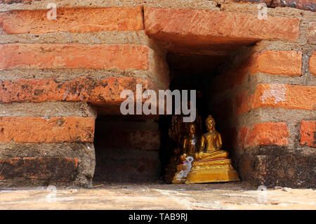 Kleine goldene Buddha Statuen in einem Red brick wall versteckt. Stockfoto