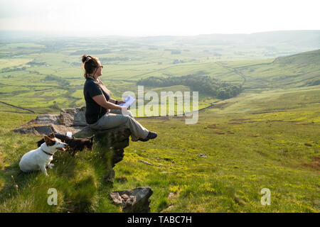 Frau draußen Genießen der schönen Aussicht in den Wald von Bowland a.o.n.b. sitzend auf einem Felsvorsprung wie "Nick's Chair" bekannt Stockfoto