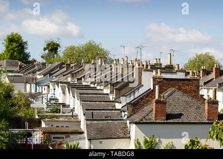 Ein Blick auf die Dächer der eine sanft geschwungene Straße von älteren viktorianischen Reihenhäusern mit Schornsteinen und Fernsehantennen. Stockfoto