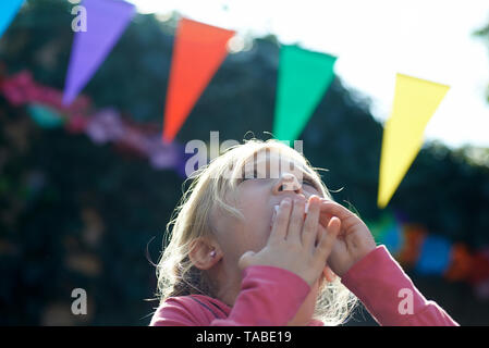 Nette junge blonde Mädchen suchen bis zu den Himmel bei einer Geburtstagsfeier von Ballons und Geburtstag Banner umgeben Stockfoto