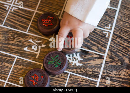 Baby hand Chinesisches Schach spielen. Die chinesischen Zeichen auf Markierung gibt den Zweig der traditionellen chinesischen militärischen Service. Stockfoto