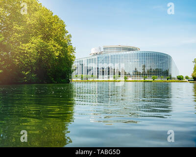Low Angle View der breiten Fassade Hauptsitz des Europäischen Parlaments in Straßburg einen Tag vor 2019 zu den Wahlen zum Europäischen Parlament - klaren blauen Himmel und ruhige Ill Wasser Sonnenlicht Flare. Stockfoto