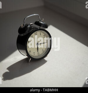 Der Wecker ist auf dem Fenster. Es zeigt Zeit um Viertel vor sechs. Stockfoto