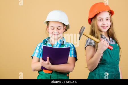 Meister Inspektor. Reparatur. glückliche Kinder. Berufliche Zukunft. Kleine Kinder im Helm mit Tablet und einem Hammer. Tag der Arbeit. 1. kleine Mädchen zusammen die Reparatur in der Werkstatt. Nach einem harten Arbeitstag müde. Stockfoto