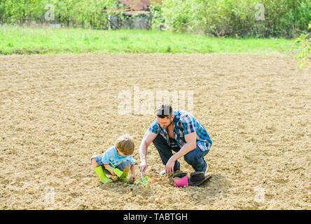 Kleiner Junge Kind helfen Vater in der Landwirtschaft. neues Leben. Böden und Düngemitteln. Vater und Sohn Blumen Pflanzen im Boden. happy Earth Day. Stammbaum. reichen natürlichen Boden. Eco Farm. Tag der Erde. Erfolgreich sein. Stockfoto