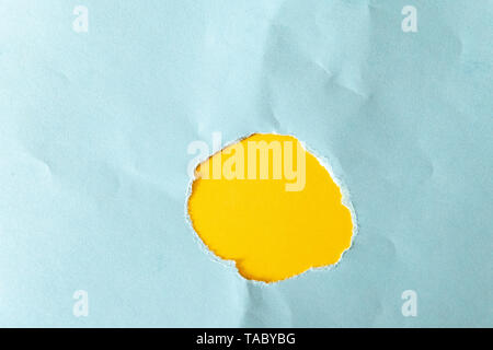 Loch in blauem Papier auf weißem Hintergrund abgerissen als Muster Stockfoto