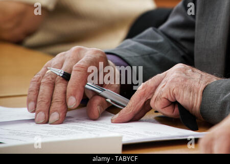 Ein älterer Mann schreibt einen Stift in den Fragebogen. Alter und Lernen. Arbeitslosigkeit und Ruhestand. Kein Gesicht Stockfoto