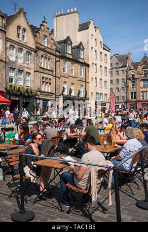 Touristen und Einheimische gleichermaßen draußen essen und genießen einige Frühsommer Sonne in Grassmarket, Edinburgh, Schottland, Großbritannien. Stockfoto