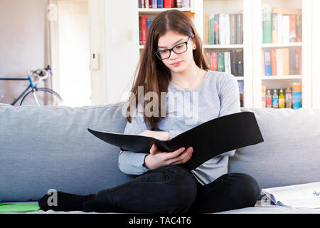 Portrait von Mädchen sitzen auf der Couch zu Hause lernen für die Schule Stockfoto
