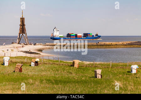 Deutschland, Niedersachsen, Cuxhaven, Nordsee, Kugel Rundumleuchte am Strand, Liegestühle am Strand, Containerschiff Stockfoto