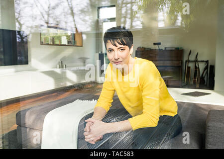Portrait von Inhalt Frau hinter Fensterglas sitzen auf der Couch im Wohnzimmer Stockfoto