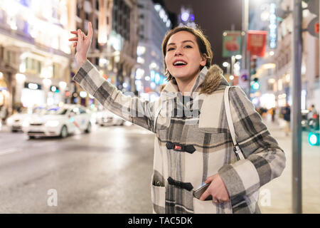 Spanien, Madrid, junge Frau in die Stadt in der Nacht neben der Gran Via hageln ein Taxi Stockfoto