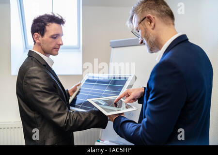 Zwei Geschäftsleute in Office mit Solarzelle und Tablet Stockfoto
