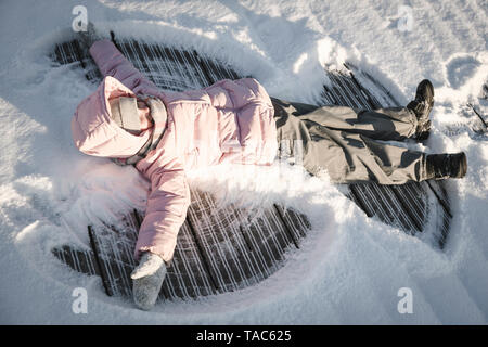 Kleines Mädchen einen Schneeengel machen Stockfoto