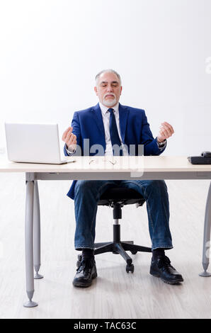 Alter Geschäftsmann Yoga Übungen im Büro Stockfoto