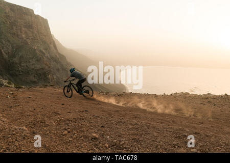 Spanien, Lanzarote, Mountainbiker auf einer Reise an der Küste bei Sonnenuntergang Stockfoto