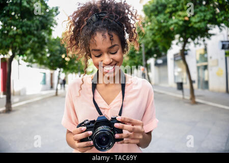 Lächelnden jungen Frau an der Kamera in der Stadt suchen Stockfoto