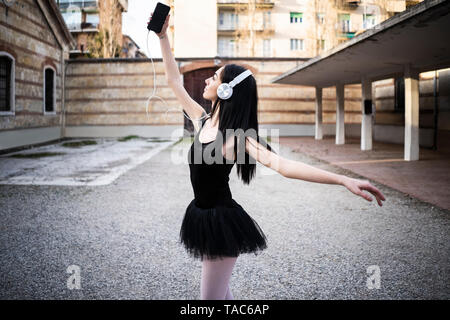 Italien, Verona, Frau im Ballett Kleid mit Handy und Kopfhörer Stockfoto