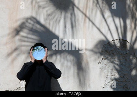 Marokko, Essaouira, Mann, eine Melone holding Spiegel vor sein Gesicht an der Wand Stockfoto