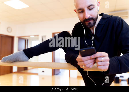 Ballet Dancer dehnen und über Handy in Ballett studio Stockfoto