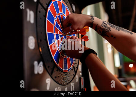 Nahaufnahme der tätowierten Mann, die Dart elektronische Dartscheibe Stockfoto