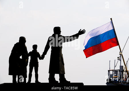 Bremerhaven, Deutschland. 23 Mai, 2019. Die Flagge der Russischen segeln Schulschiff 'Mir' winkt am Abend neben der Familie Skulptur der Emigration Memorial" (von Frank Varga erstellt im Jahr 1986). Credit: mohssen Assanimoghaddam/dpa/Alamy leben Nachrichten Stockfoto