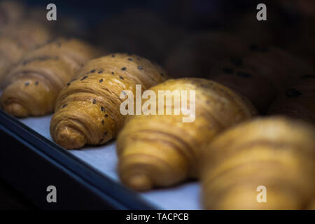 Croissant auf Bäckerei Regal. Französische Backwaren Brot. Frisch und lecker buttrige Croissants mit schwarzem Sesam auf die Oberseite. Brunch oder Morgen Vorspeise Nahaufnahme. Europ. Stockfoto