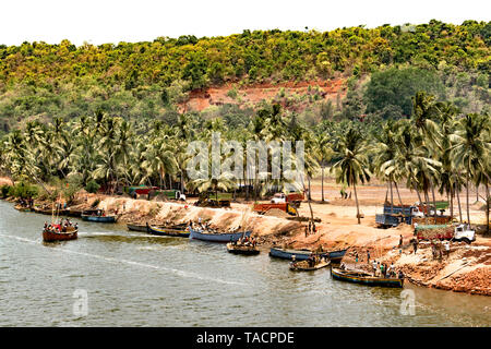 Dorf an der Küste des Indischen, mit vielen Palmen neben River Bank. Arbeiter Bergbau Sand von Auen in kleinen Booten, und das Beladen der Lkw Stockfoto