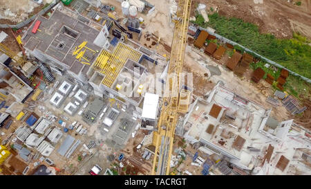 Baustelle - Luftbild eines großen Wohn- verbindung während der frühen Phasen der Konstruktion, mit Kränen und grünen Umgebung. Stockfoto