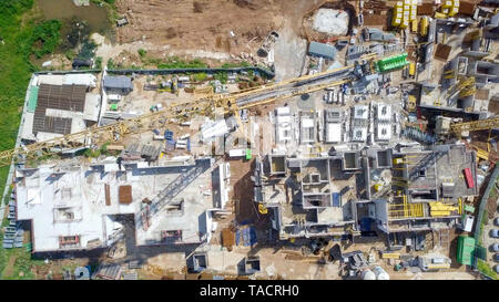 Baustelle - Luftbild eines großen Wohn- verbindung während der frühen Phasen der Konstruktion, mit Kränen und grünen Umgebung. Stockfoto