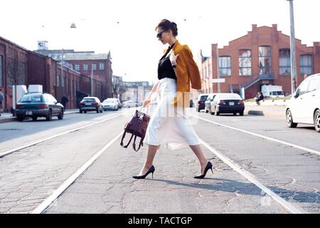 Glückliche junge geschäftsfrau zu Fuß auf der Straße. Stockfoto