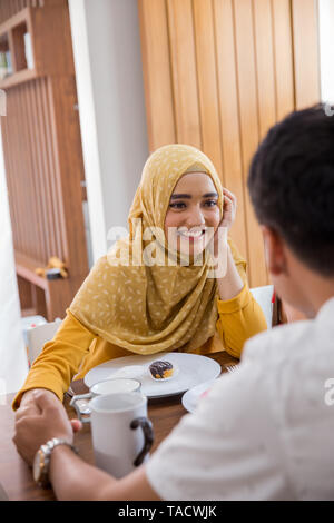 Eltern halten sich an den Händen, während das Frühstück Stockfoto
