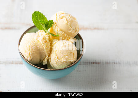 Vanilleeis Kugeln mit Minze in einem türkis Schüssel auf eine weiße Holztisch Stockfoto