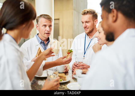 Gruppe von Ärzten in der Cafeteria oder Kantine essen und entspannen small talk Stockfoto