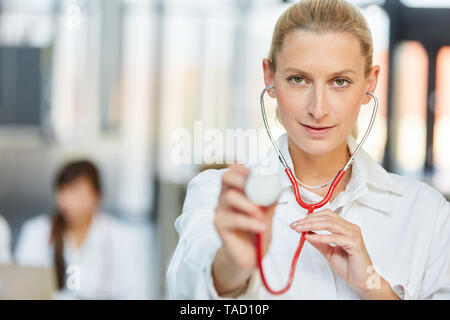 Junge Frau Doktor mit Stethoskop als Internist oder Spezialisten im Krankenhaus Stockfoto