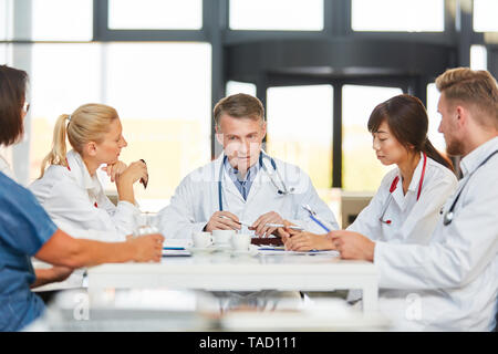 Leitender Arzt bespricht die Zusammenarbeit mit Kollegen und Krankenschwestern im Team Stockfoto