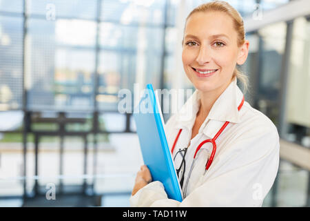 Junge freundliche Ärztin in Ausbildung oder als medizinische Assistentin mit Patientenakte Stockfoto