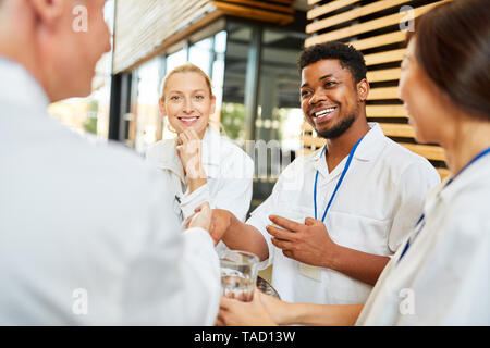 Junge afrikanische medizin student begrüßt leitender Arzt mit Handshake in Kaffeepause Stockfoto