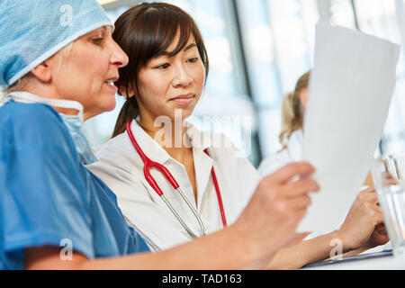 Chirurg und junge weibliche Arzt einen Patienten in der Notaufnahme zu diskutieren Stockfoto